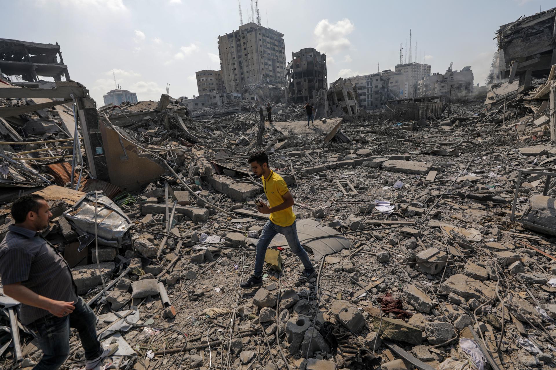 Palestinos caminan entre los escombros