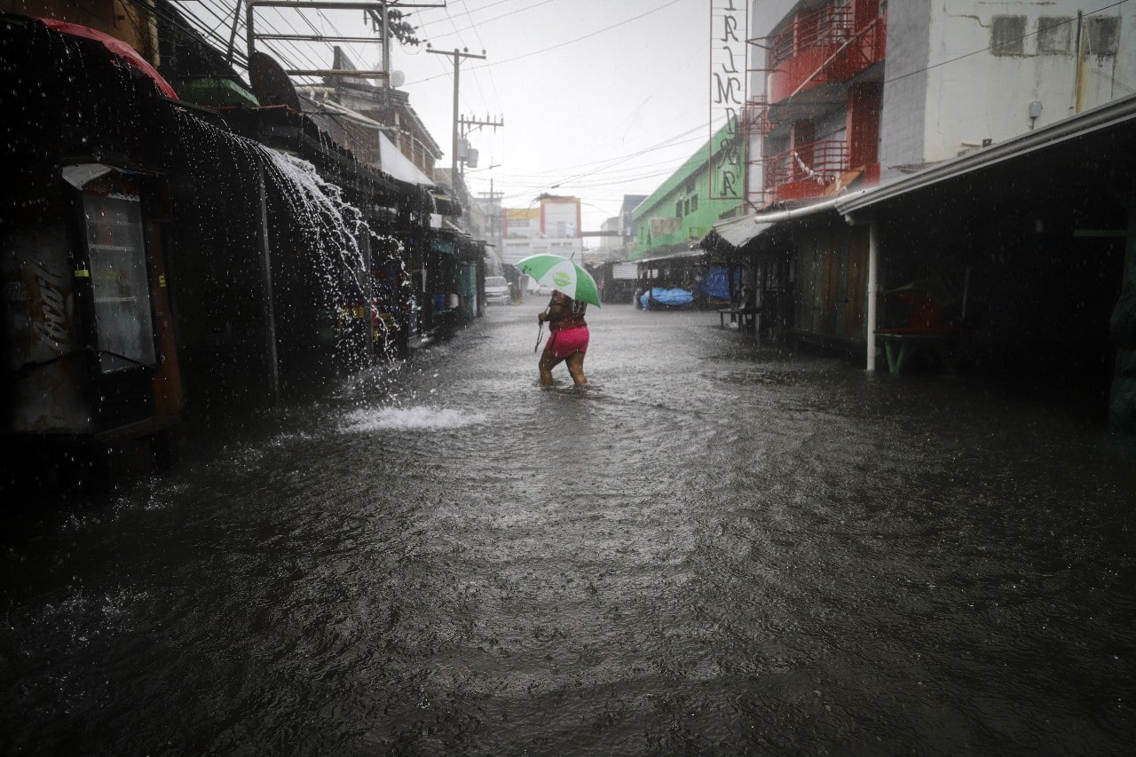 Una mujer camina por una calle inundada durante el paso de la tormenta tropical Sara en La Ceiba, Honduras.