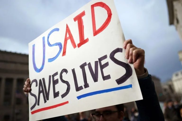 An American displays a sign with the message “Usaid saves lives”
