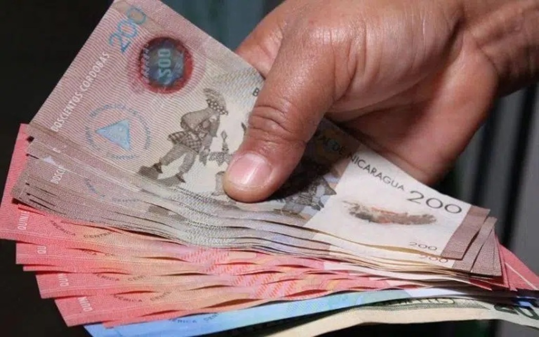 Un ciudadano muestra un fajo de billetes de 200, 500 y 100 córdobas.