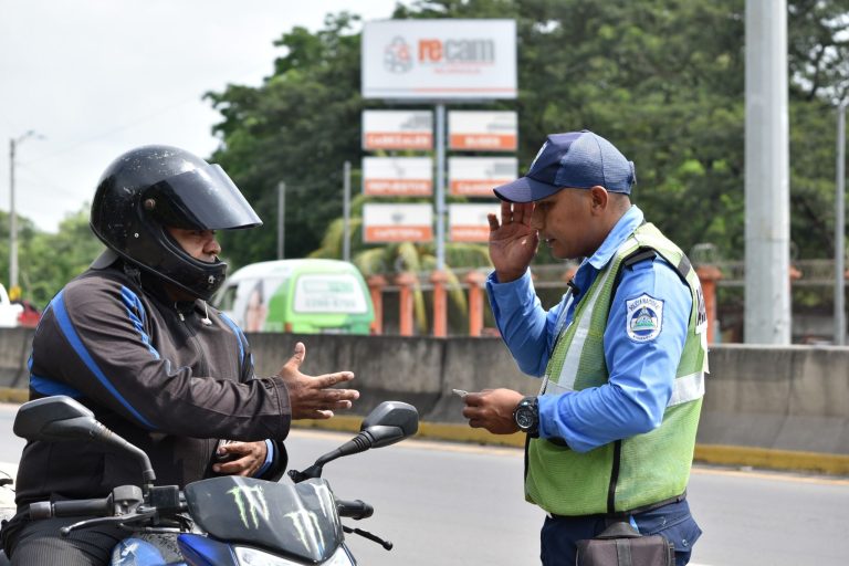 Oficial de tránsito de la Policía Nacional haciendo una revisión a un motorizado