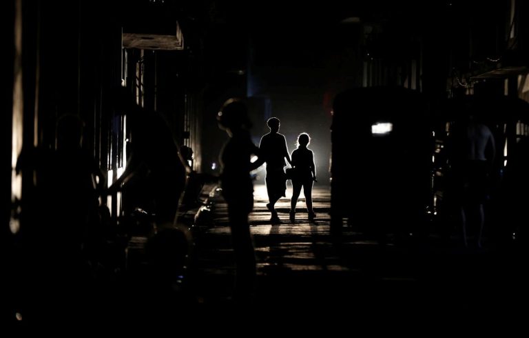 Unos ciudadanos caminan por una calle oscura en La Habana
