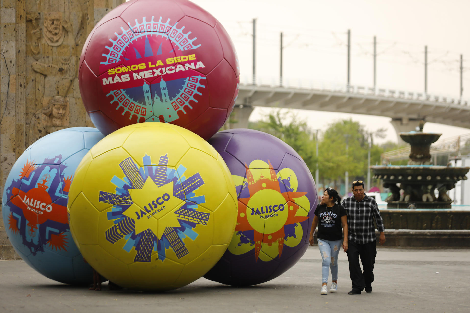 Personas caminan junto a balones gigantes que representan la cultura y tradición mexicana, en la ciudad de Guadalajara.