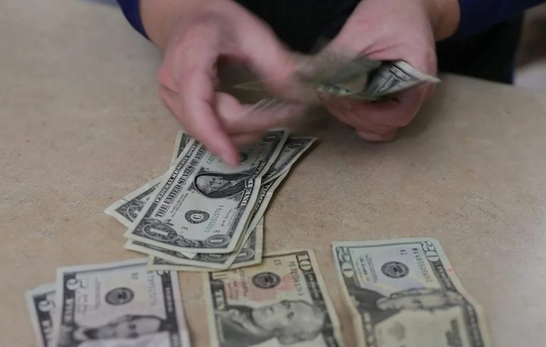 Una persona cuenta unos billetes de dólares.