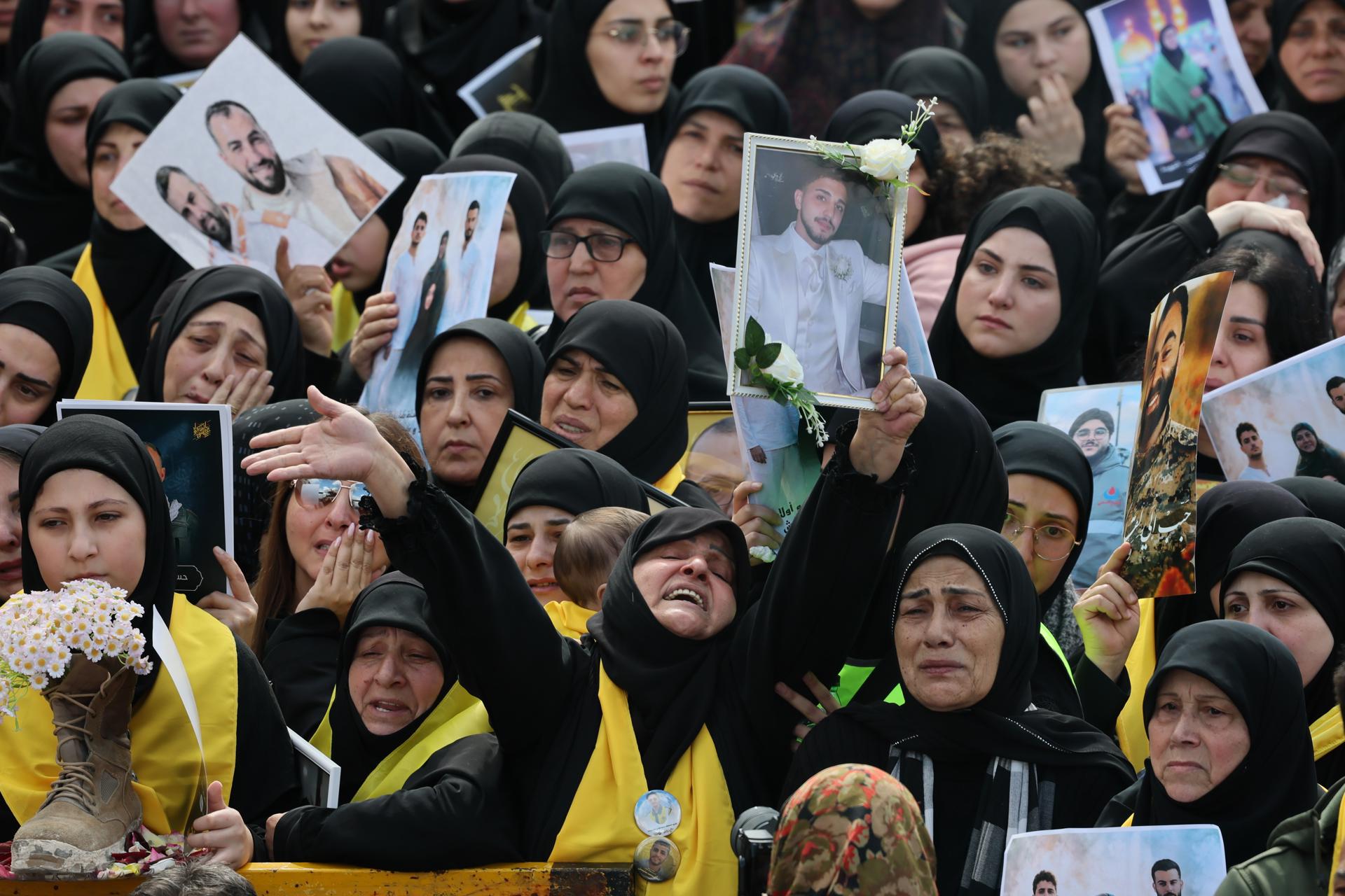 Personas sostienen retratos de combatientes de Hezbolá, que murieron antes del alto el fuego entre Hezbolá e Israel.